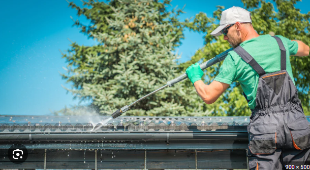 Perfect Pane technician clearing and rinsing roof gutters from above