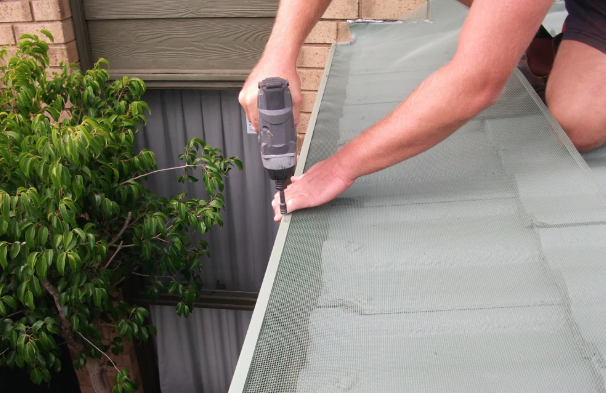 Technician securing a mesh gutter guard down onto the roof edge