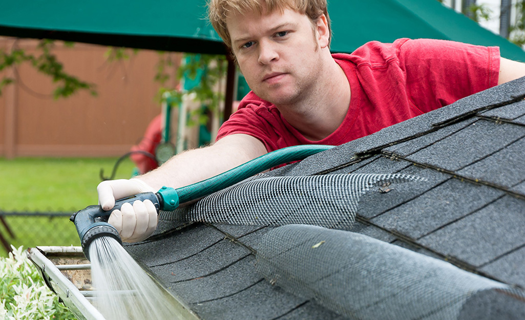 Technician flushing a gutter run clean with a pressure washer