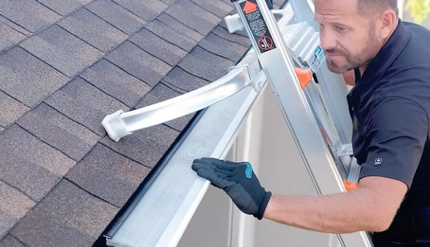 Technician on a ladder fitting a gutter guard section into place during a North Bay installation