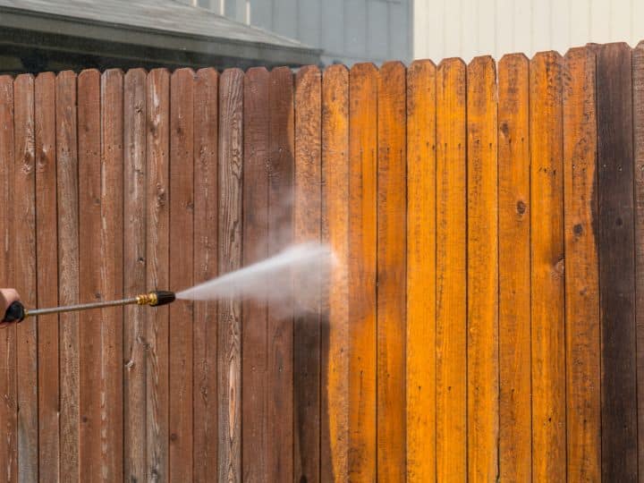 Wood fence in Vacaville being cleaned of green buildup with a pressure washer