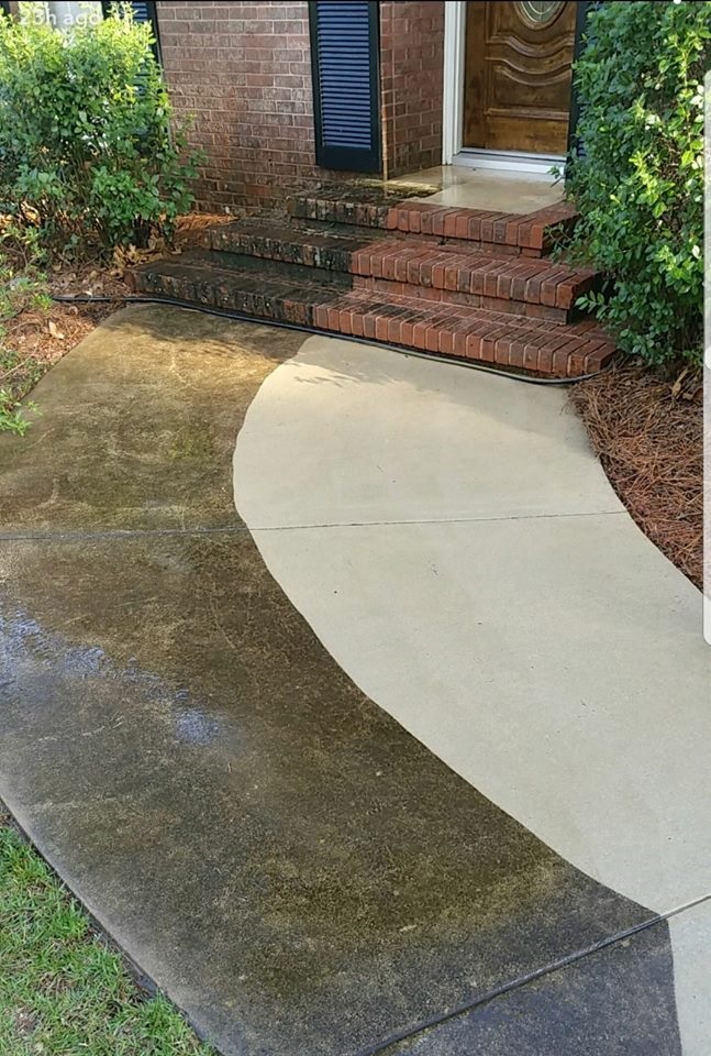 Concrete driveway being power-washed clean of grime