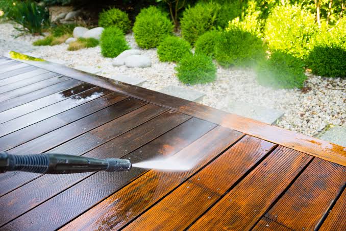 Technician power-washing green algae off a home's siding