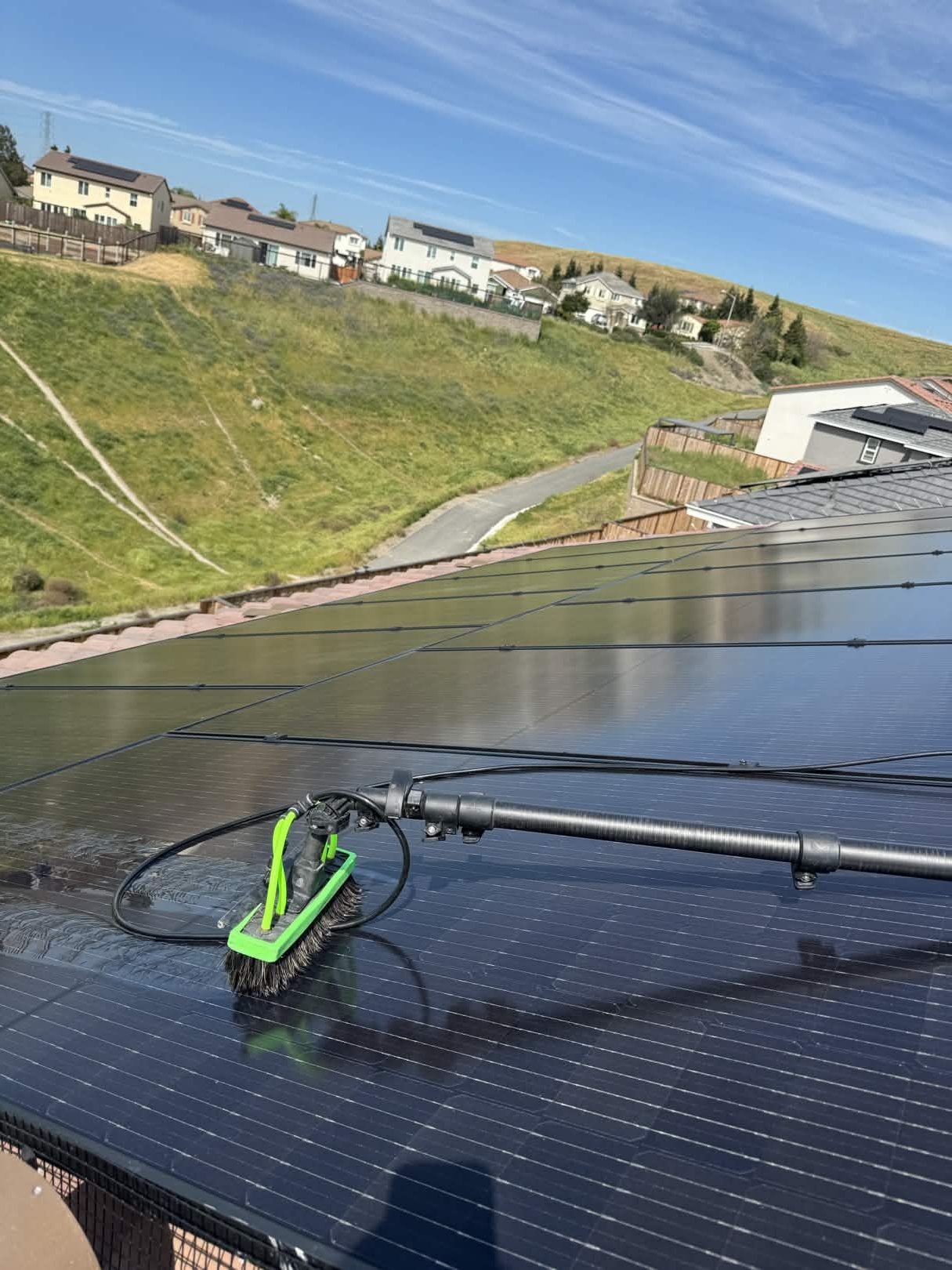 Soft-bristle brush and water-fed pole used for solar panel cleaning on a clean Crockett rooftop array