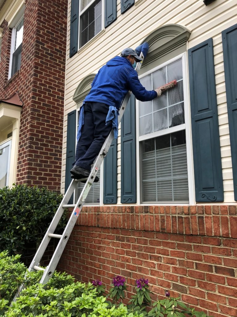 Technician cleaning second-story windows on a North Bay home with a pool