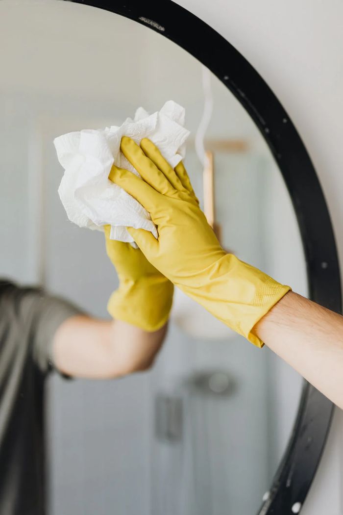 Wiping down a round mirror with a cloth
