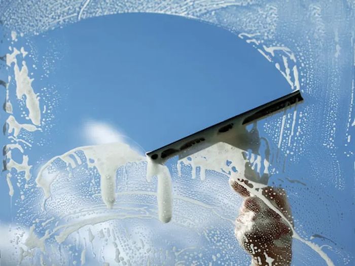 Squeegee clearing soapy water off a window