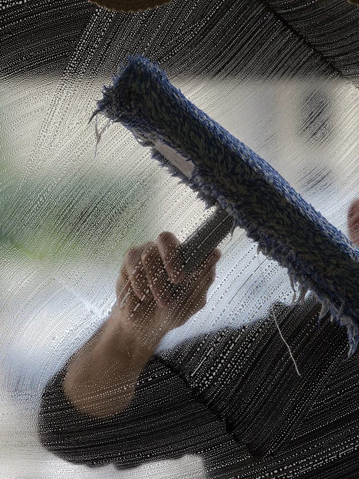 Vallejo window cleaning technician washing a window with a soft scrubber, seen through the glass